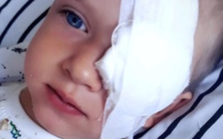 Dziecko z opatrunkiem na oku, wygląda na zmartwione.