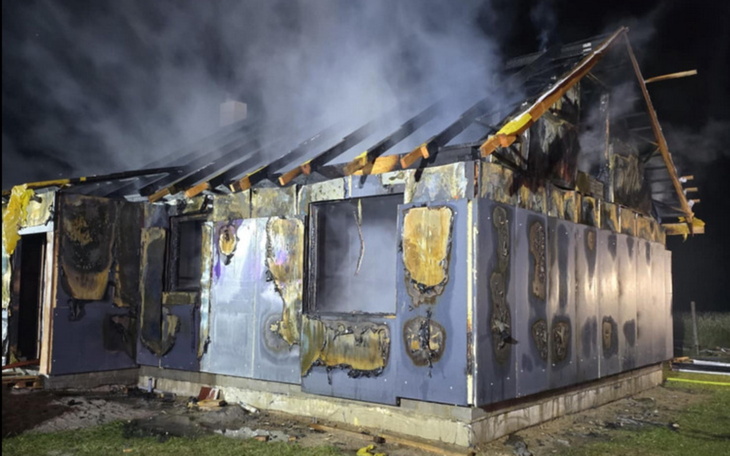 Zniszczony dom po pożarze, z dymem unoszącym się nad dachem.