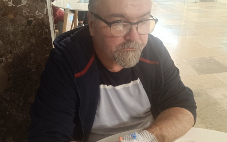 Mężczyzna w okularach siedzący przy stole, z zamyśloną miną.