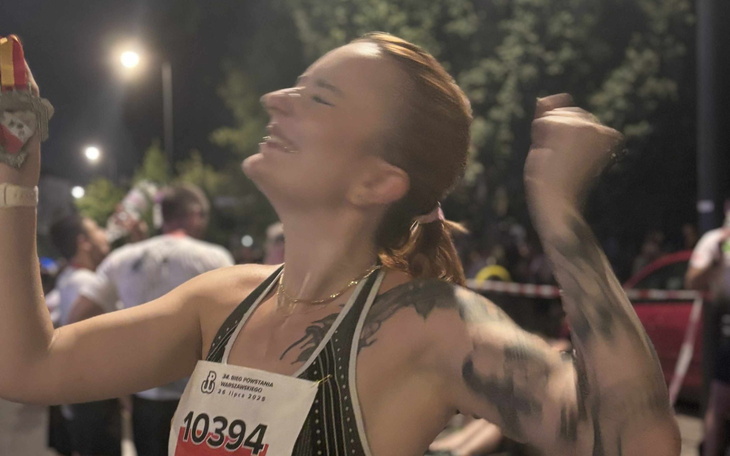 Kobieta cieszy się po ukończeniu biegu, z uśmiechem na twarzy.