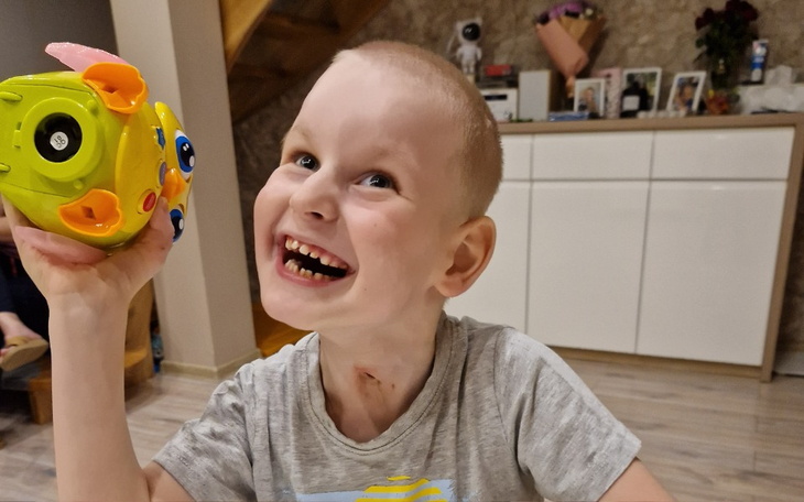 Chłopiec z uśmiechem trzymający zabawkę w ręku.