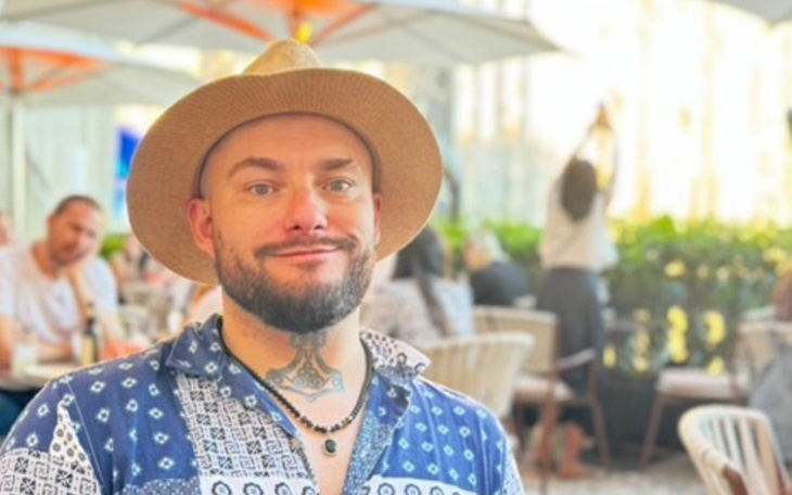 Mężczyzna z tatuażem, uśmiechający się w restauracji.