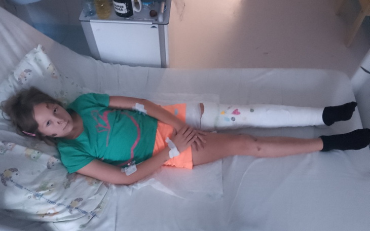 Dziewczynka leżąca w szpitalnym łóżku z opatrunkami.