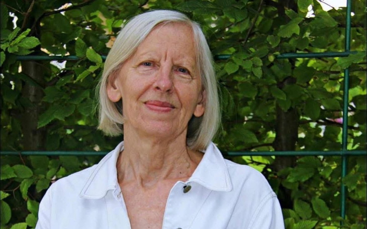 Starsza kobieta uśmiechająca się wśród zieleni.