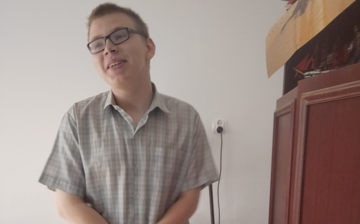 Młody mężczyzna uśmiechający się w jasnym pomieszczeniu.