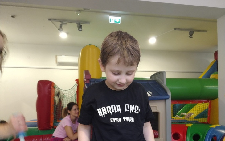 Chłopiec bawi się w kolorowym placu zabaw, uśmiechnięty i szczęśliwy.