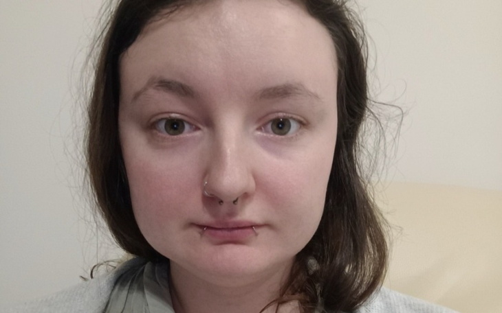 Portret młodej kobiety z delikatnym makijażem i kolczykiem w nosie.