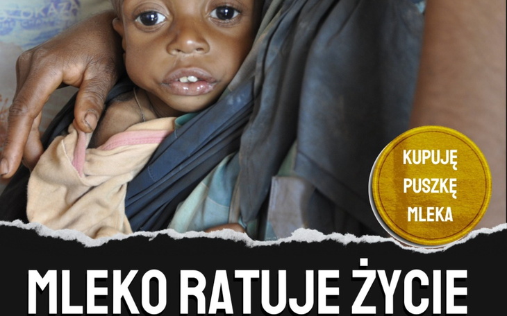 Małe dziecko w ramionach opiekuna, blisko, z odsłoniętą twarzą.
