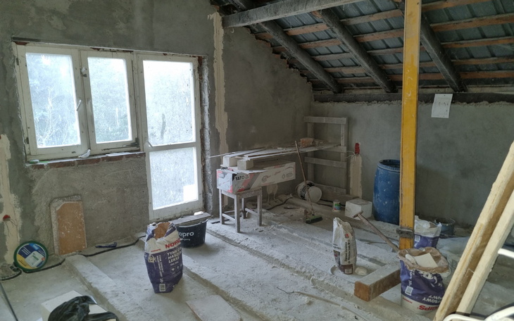 Wnętrze w trakcie remontu, z widokiem na okno i materiały budowlane.