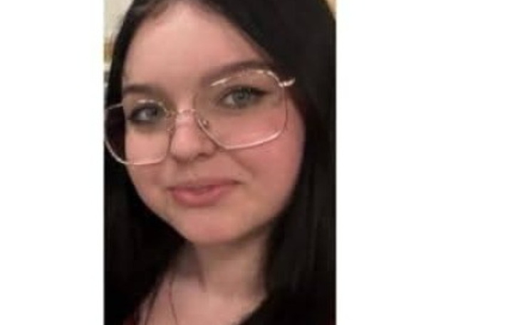 Portret dziewczyny w okularach, uśmiechającej się do kamery.