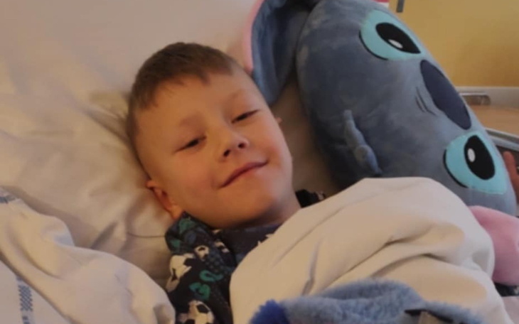 Chłopiec w szpitalnym łóżku z pluszowym misiem.