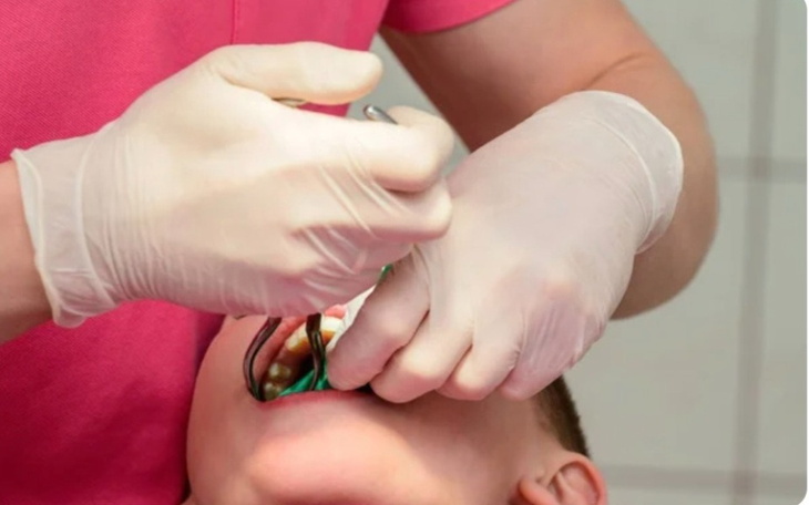 Dentysta wykonuje zabieg na zębach dziecka.