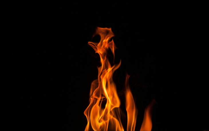 Płomień ognia na czarnym tle, tworzący dynamiczny kształt.
