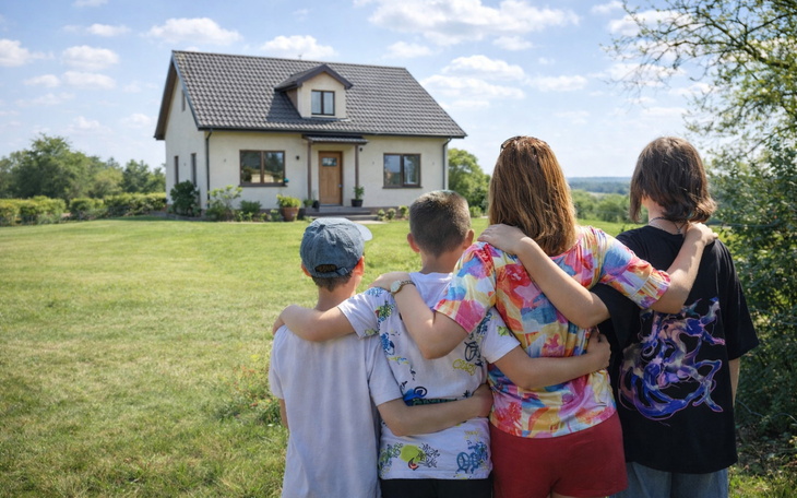 Czwórka dzieci patrzy na dom z uśmiechami na twarzach.