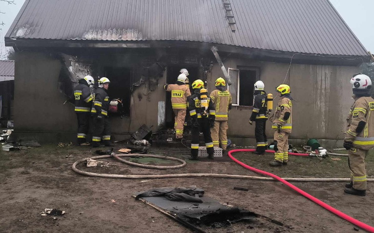 Strażacy pracują przy zniszczonym budynku po pożarze.