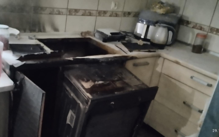 Zniszczona kuchnia z uszkodzoną szafką i sprzętem.