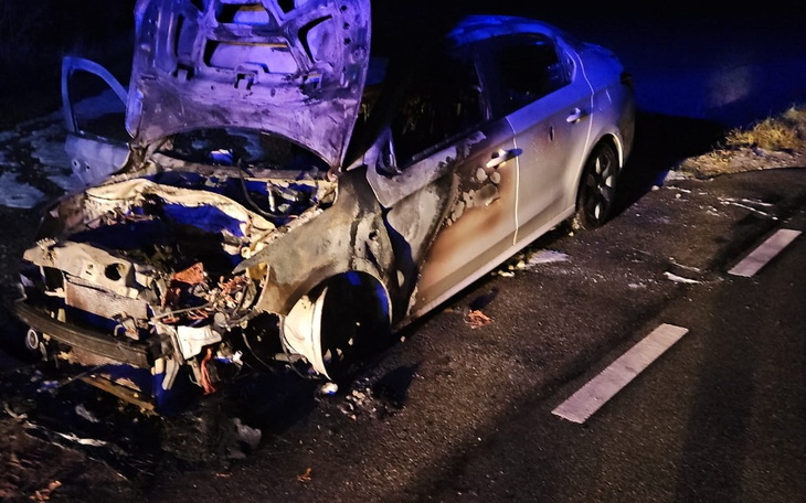 Spalony samochód na drodze, zniszczony przez ogień.