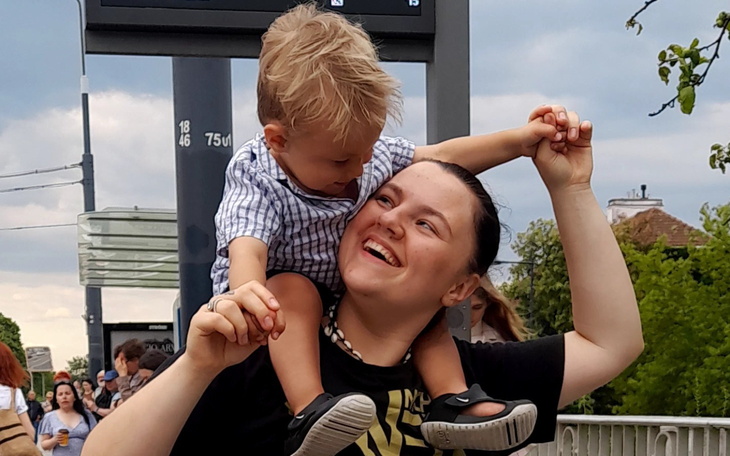 Mama z dzieckiem na rękach, oboje uśmiechnięci.