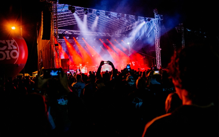 Tłum ludzi na koncercie, z efektami świetlnymi w tle.