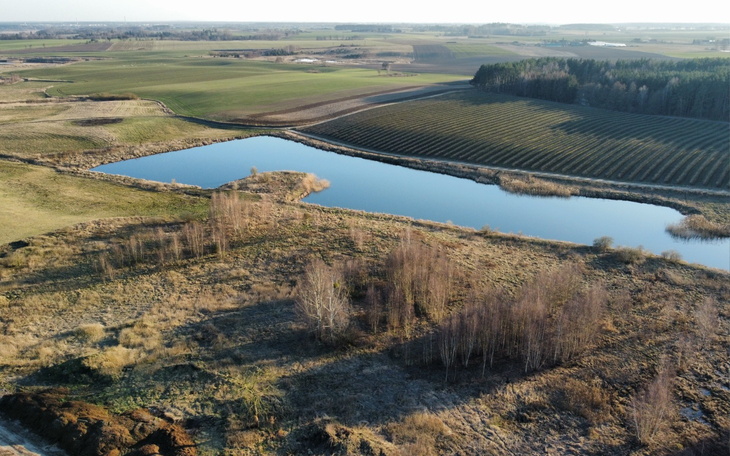 Malowniczy krajobraz z jeziorem otoczonym zielonymi polami.