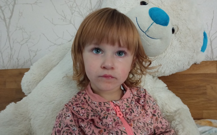 Mała dziewczynka z pluszowym misiem na łóżku.