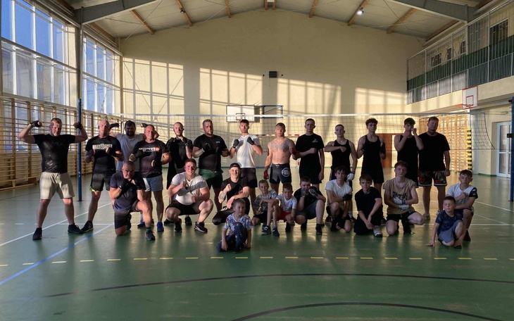 Grupa ludzi na treningu sportowym w hali.