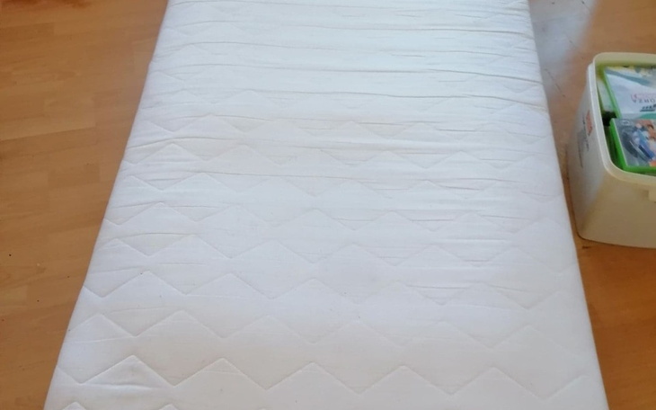 Pusty materac na podłodze, w jasnym pomieszczeniu.