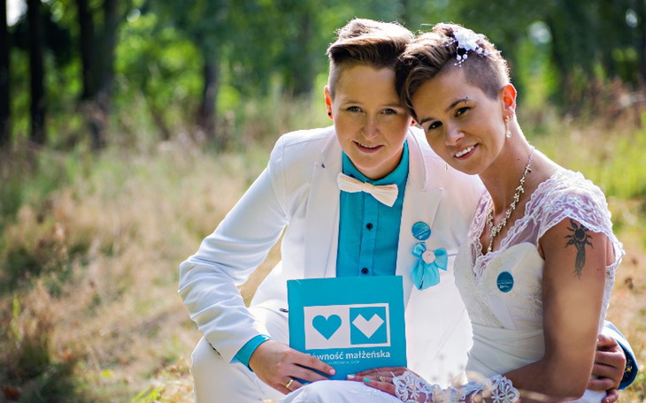 Para młoda w plenerze, trzymająca tabliczkę z sercami.