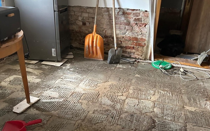 Pomieszczenie w trakcie remontu, z widocznymi narzędziami i brudem.