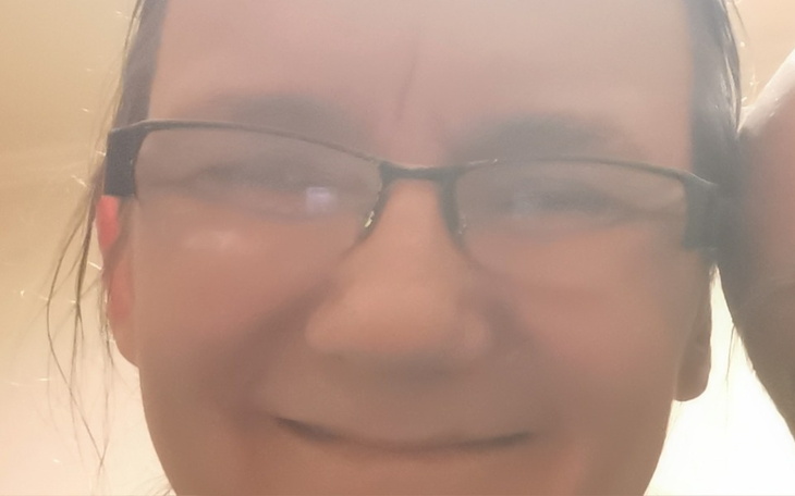 Osoba w okularach z uśmiechem na twarzy.