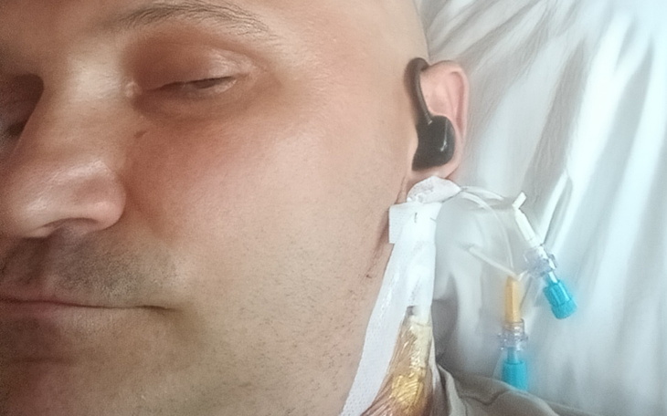 Mężczyzna w szpitalu, z cewnikiem i słuchawkami.