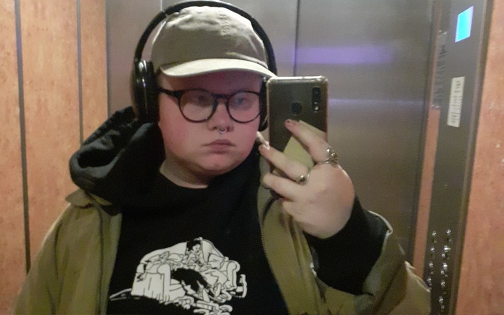 Osoba w windzie robiąca selfie z słuchawkami.