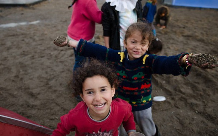 Dzieci bawiące się w piasku, uśmiechnięte i radosne.