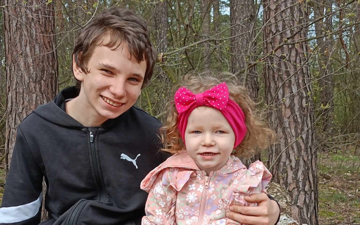 Chłopiec z dziewczynką w lesie, oboje się uśmiechają.