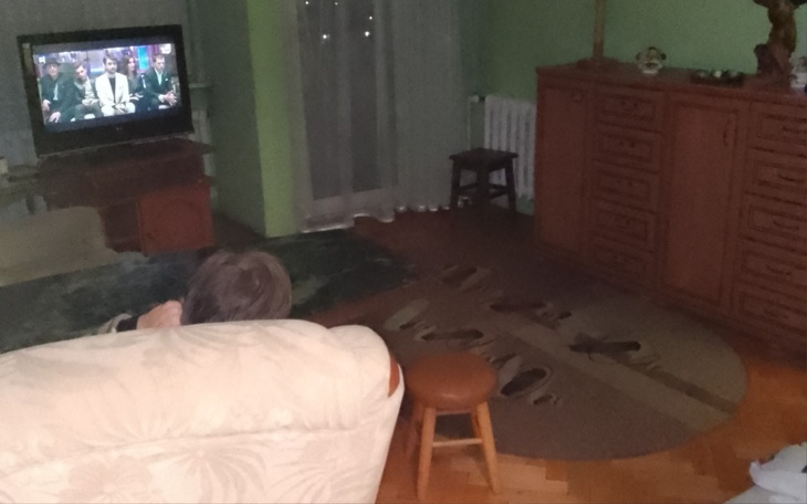 Osoba oglądająca telewizję w przytulnym salonie.