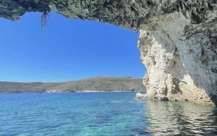 Widok na morze z jaskini, błękitna woda i skały.