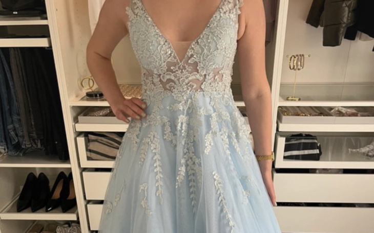 Kobieta w niebieskiej sukni, pozująca w eleganckim wnętrzu.