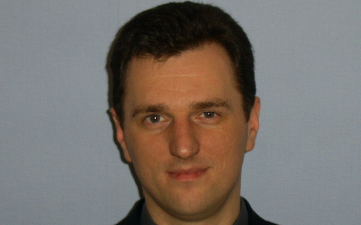 Mężczyzna w garniturze, uśmiechający się do kamery.