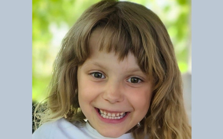 Uśmiechnięta dziewczynka z długimi włosami.