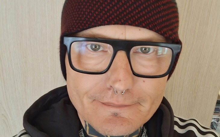 Mężczyzna w okularach i czapce, uśmiechający się do kamery.