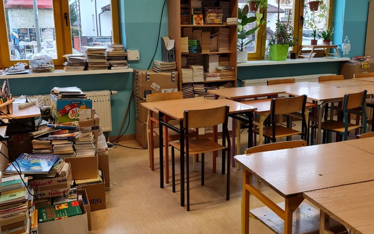 Wnętrze biblioteki z książkami i pustymi stolikami.