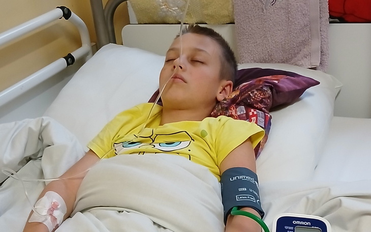 Chłopiec w szpitalu, leży z zamkniętymi oczami.