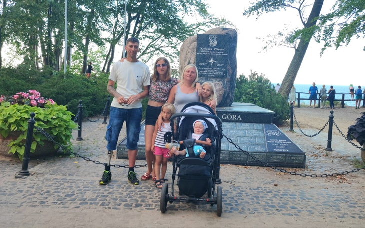 Rodzina przy pomniku, z dzieckiem w wózku.