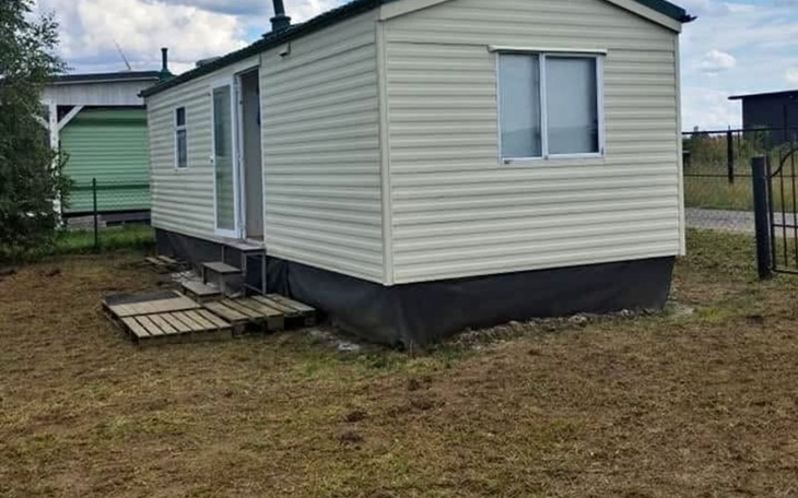 Dom mobilny na działce, otoczony trawnikiem.