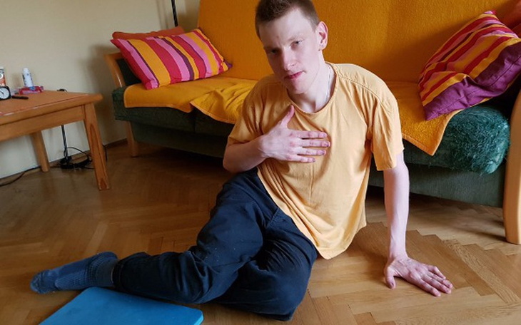 Mężczyzna w żółtej koszulce, siedzący na podłodze.