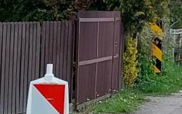Ogrodzenie z bramą i znakiem drogowym.