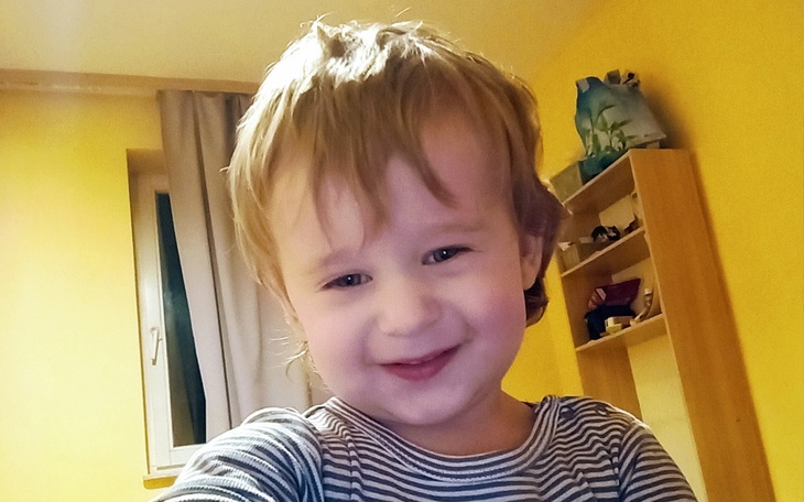 Mały chłopiec uśmiecha się do kamery w kolorowym pokoju.