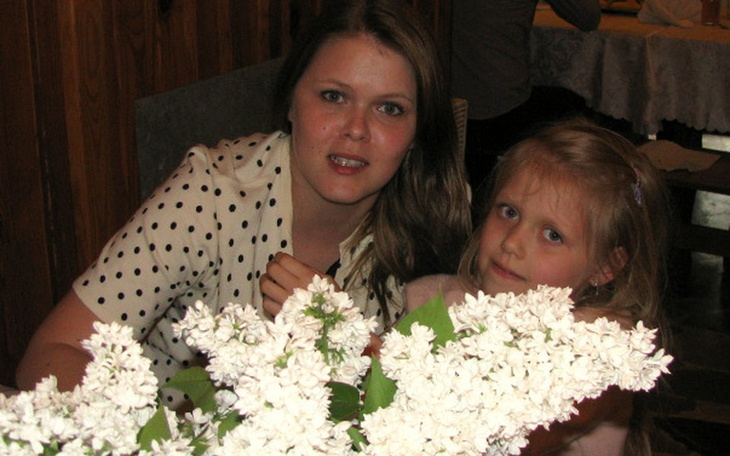 Matka z córką przy bukiecie białych kwiatów.