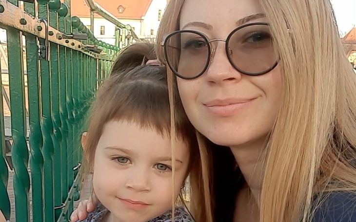 Matka z córką na tle architektury, uśmiechnięte i szczęśliwe.