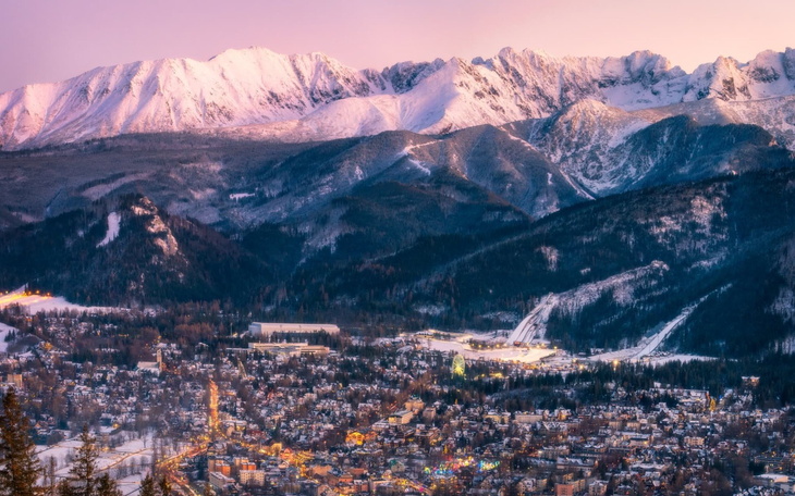 Panorama gór z ośnieżonymi szczytami i miastem w dolinie.